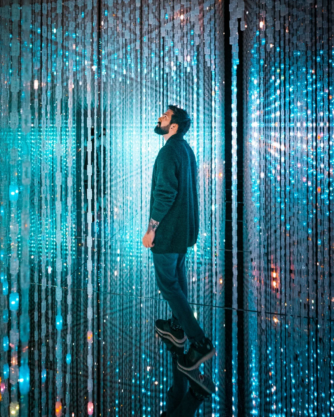 Visitor between blue light strands at TeamLab